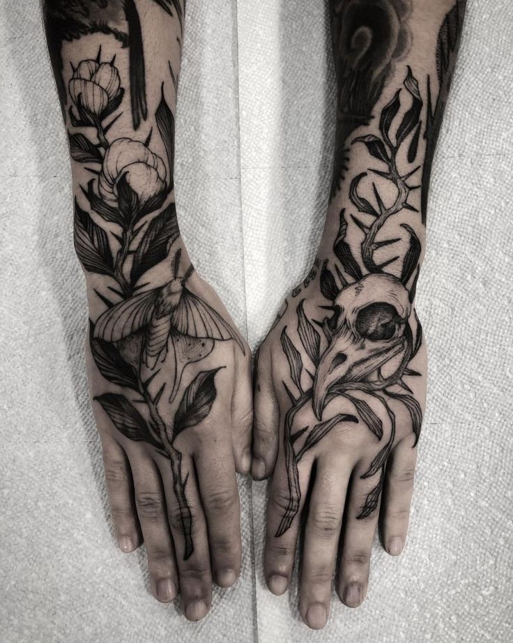 two hands that have tattoos on them with flowers and birds in the middle one is black and white