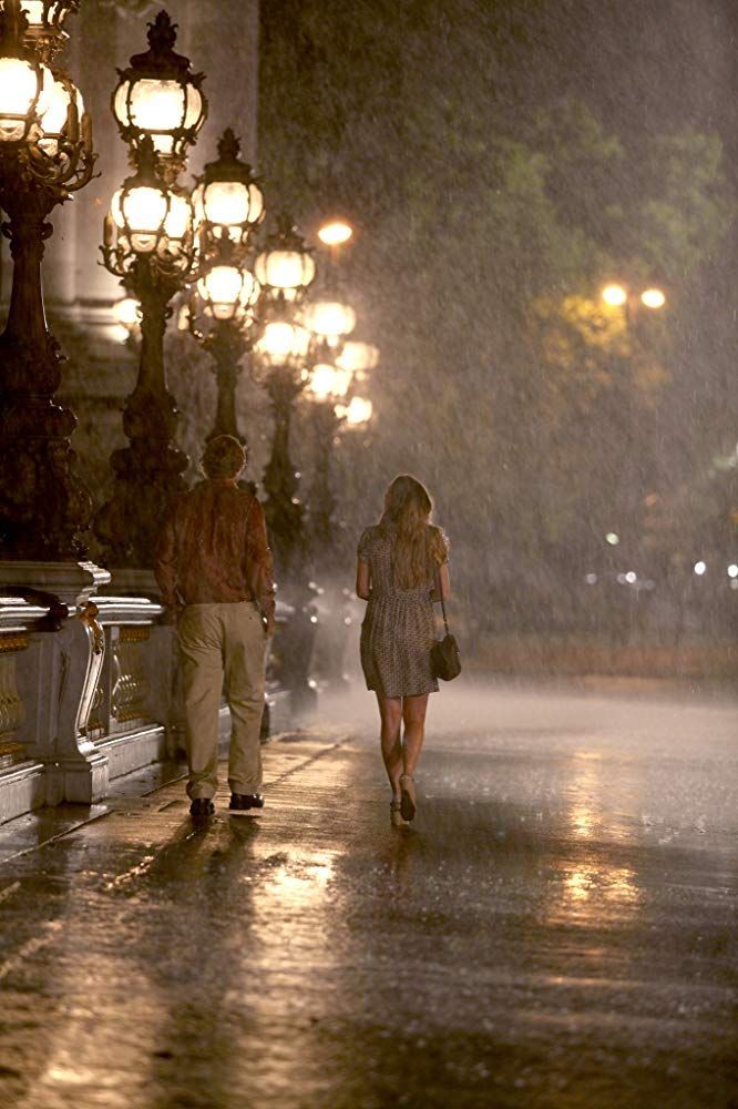 two people walking down the street in the rain