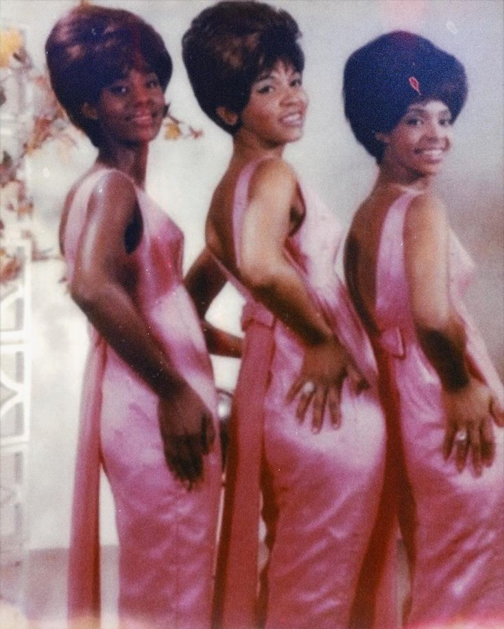 three women in pink dresses standing next to each other with their hands on their hips