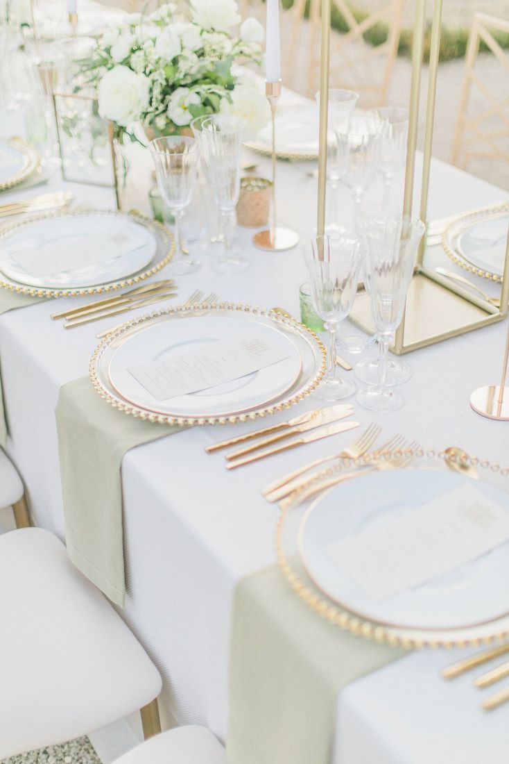 the table is set with white and gold place settings