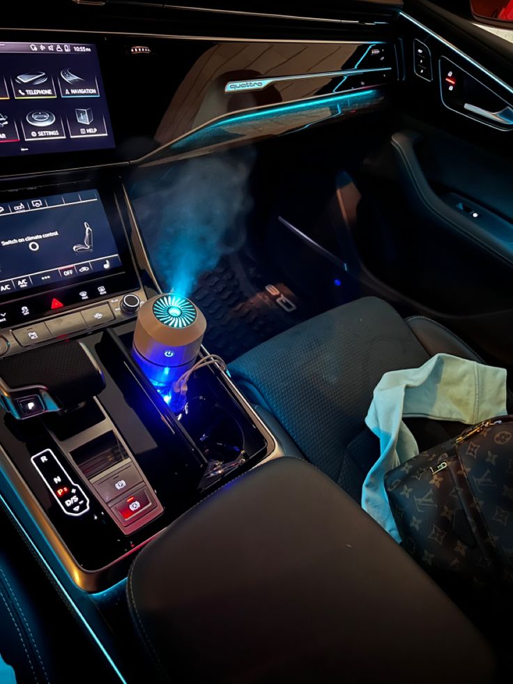 the interior of a modern car with blue lights and electronic controls on it's dashboard