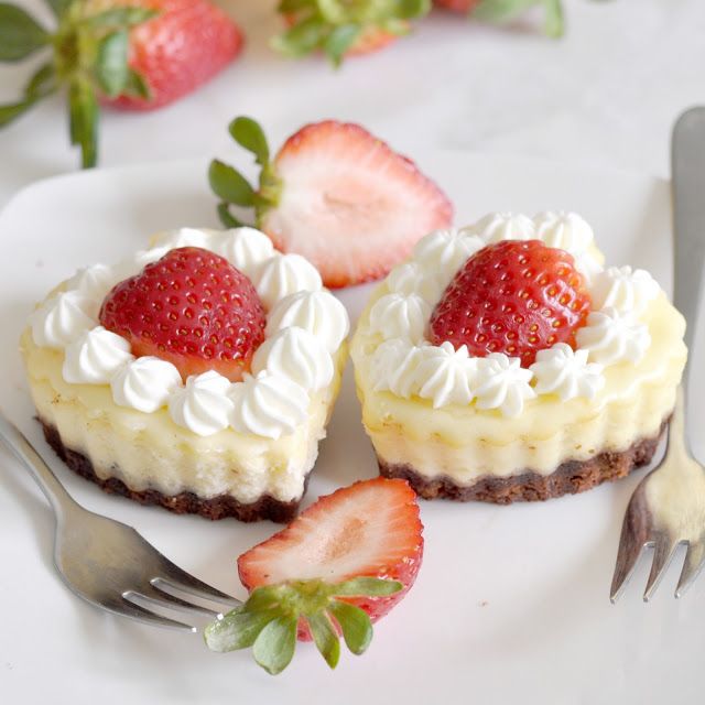 two desserts on a plate with strawberries next to each other and one has a fork