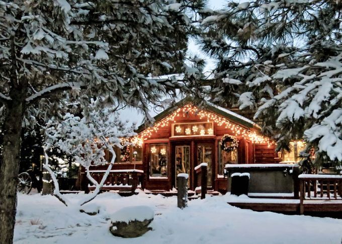 a small cabin with christmas lights on it's roof in the snow stock photo