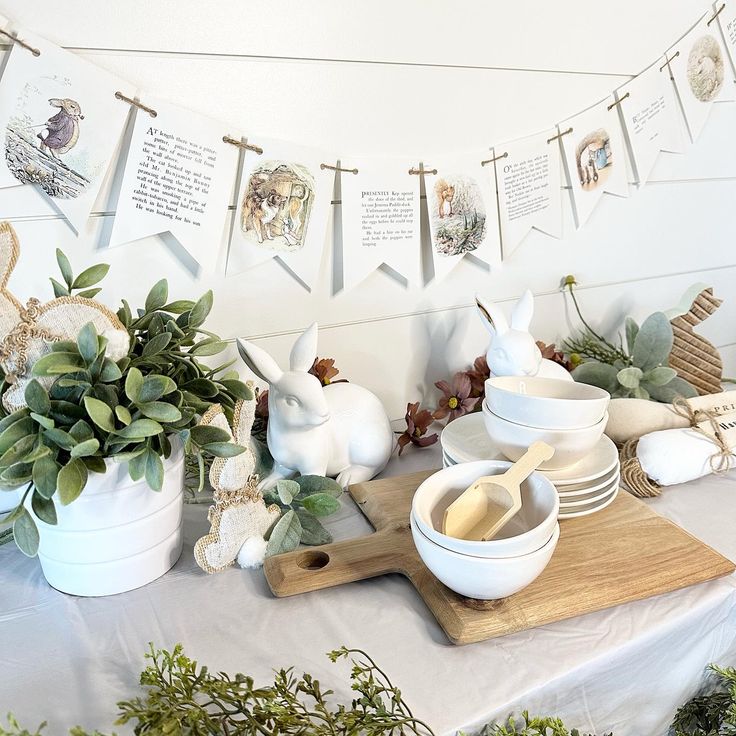 a table topped with bowls and plates covered in greenery next to bunting banners