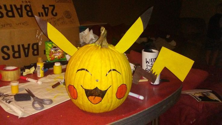 a pumpkin decorated with pikachu faces and two knives on top of a table