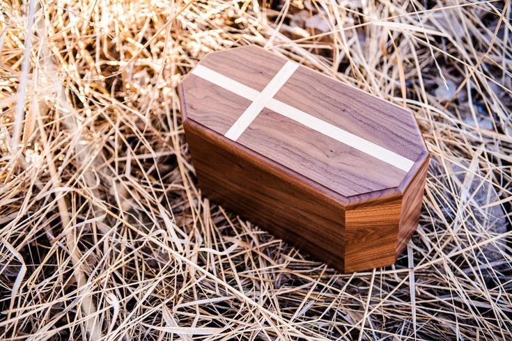 a wooden box with a white cross on it sitting in the middle of dry grass