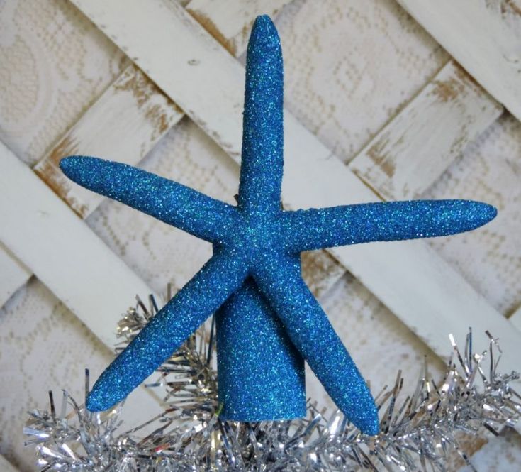 a blue starfish ornament sitting on top of a silver tinsel christmas tree