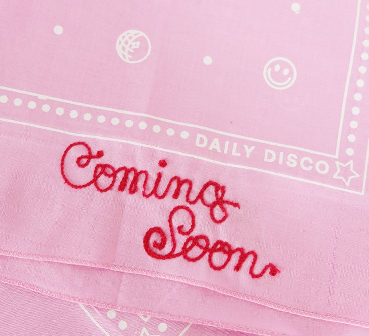 a pink cloth with the words coming soon embroidered on it