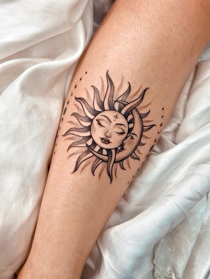 a woman's leg with a sun and moon tattoo on the left side of her arm