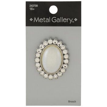 the metal gallery brooch with white flowers on it's center is packaged in a package