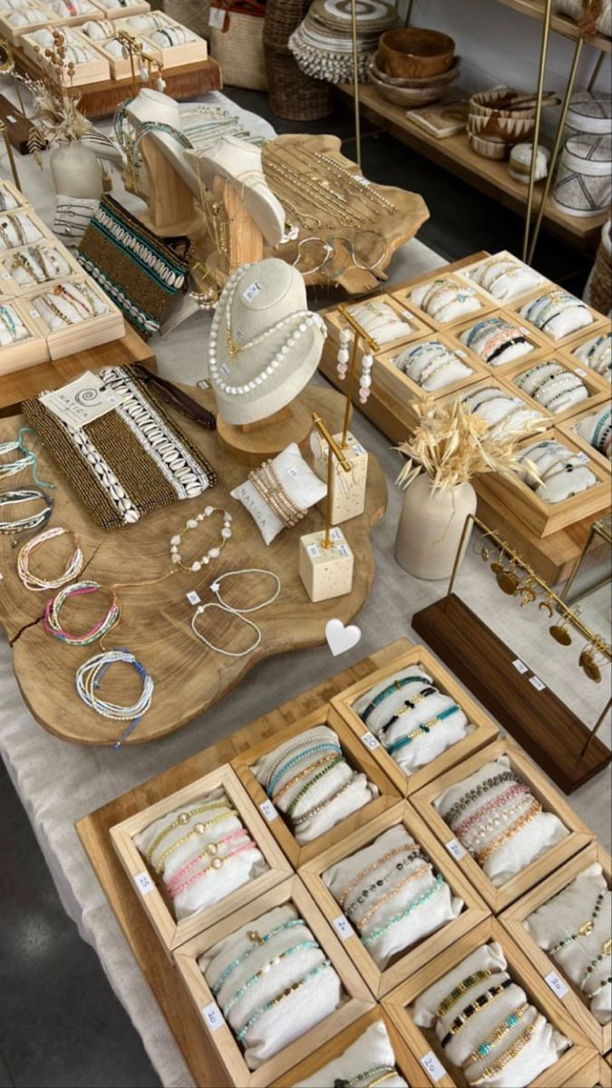 an assortment of bracelets and necklaces on display at a market stall with wooden trays