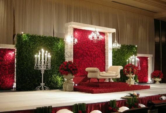 a red and white stage set up for a wedding ceremony with candles on the side