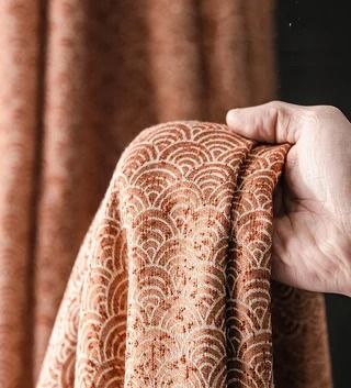 a person holding up a piece of fabric with an intricate design on the top and bottom