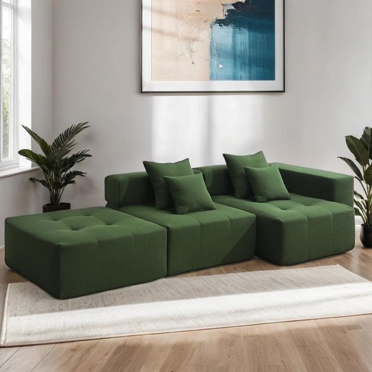 a green couch sitting on top of a wooden floor next to a potted plant