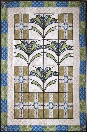 a quilted wall hanging with blue and green designs on it's sides, in the shape of an art deco fan