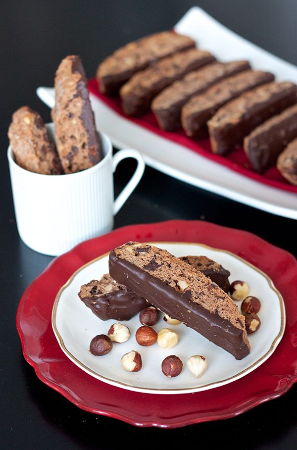 two plates filled with chocolate and nuts on top of a black table next to another plate full of cookies