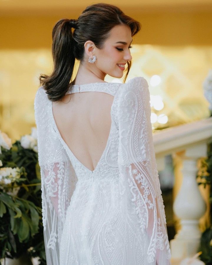 the back of a woman's wedding dress with long sleeves and an open neckline