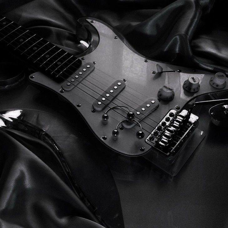 an electric guitar laying on top of a black cloth