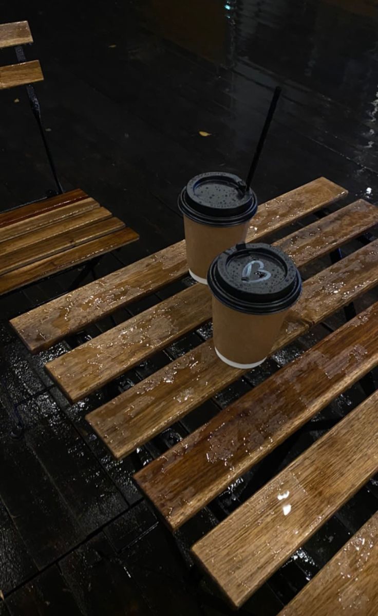 two coffee cups sitting on top of wooden benches