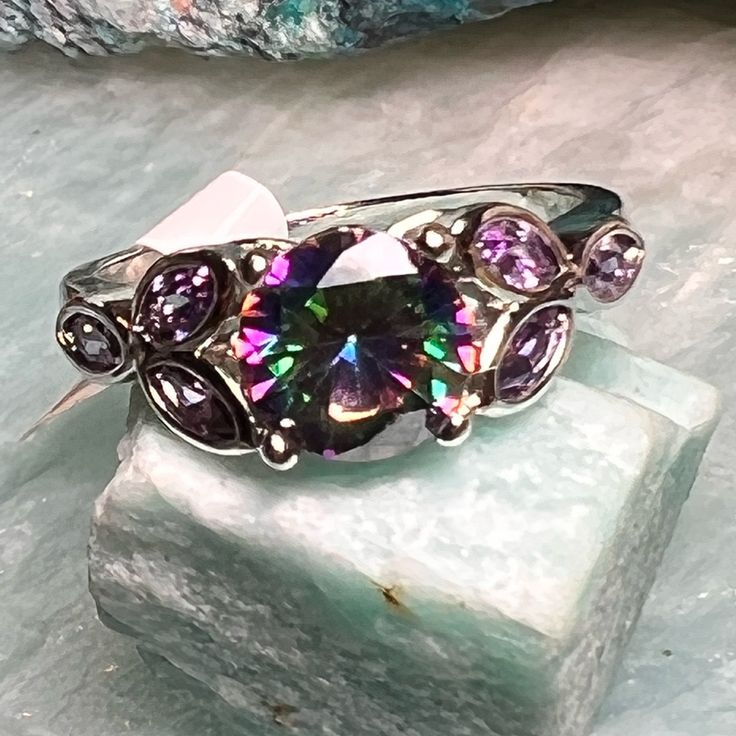 Beautiful Silver Tone Size 9 , 8, 7 Or 6 Ring With A Simulated Mystic Topaz Center Stone And 3 Small Simulated Amethyst Stones On Each Side. Ring Has A 925 Stamp However This Has Been Tested And Was Negative For Precious Metals Therefore Has An Overlay Or Plating Only. All Stones Have Been Verified As Simulated Or Lab Created. Ring Is As Pictured. This Listing Is For A Ring Only. Tag Is Handmade. All Shipping Is Recorded In Its Entirety. Summarized Pics Will Be Sent To You. I Cannot Be Held Acco Iridescent Crystal Ring With Gemstone For Anniversary, Iridescent Crystal Gemstone Ring For Anniversary, Iridescent Multi-stone Round Rings, Anniversary Iridescent Crystal Ring With Gemstone, Mystical Silver Amethyst Ring, Iridescent Jewelry With Accent Stones For Anniversary, Iridescent Multi-stone Ring For Anniversary, Iridescent Multi-stone Anniversary Rings, Iridescent Multi-stone Sterling Silver Jewelry