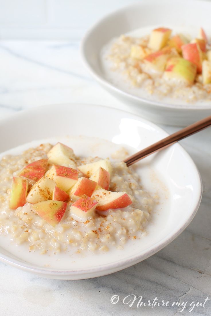 two white bowls filled with oatmeal topped with apples