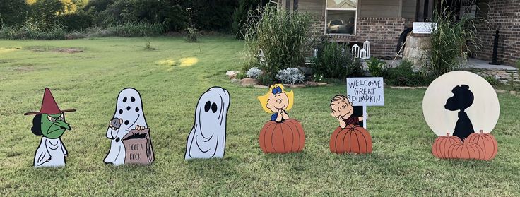 halloween yard decorations in front of a house with pumpkins and ghost on the lawn