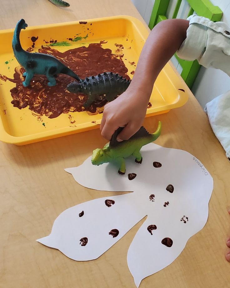 a child is playing with dinosaur paper and glue