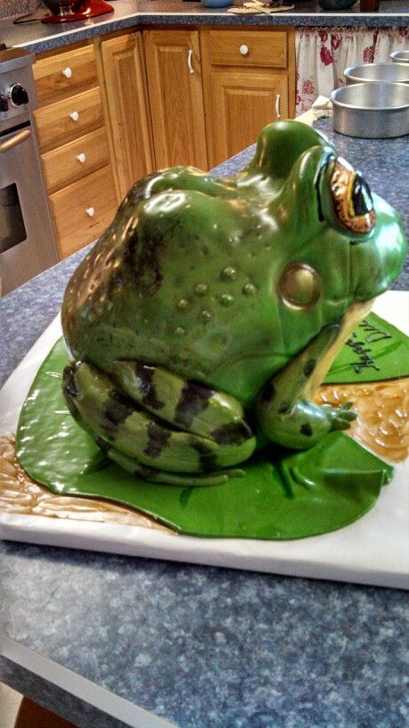 a cake shaped like a frog sitting on top of a counter next to a stove