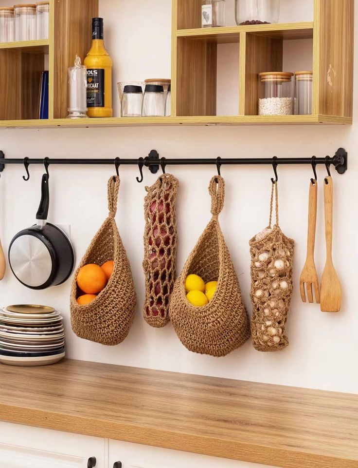 kitchen utensils hanging from hooks on the wall above a wooden counter top with plates and bowls