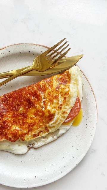 a white plate topped with an omelet covered in cheese and sauce next to a fork