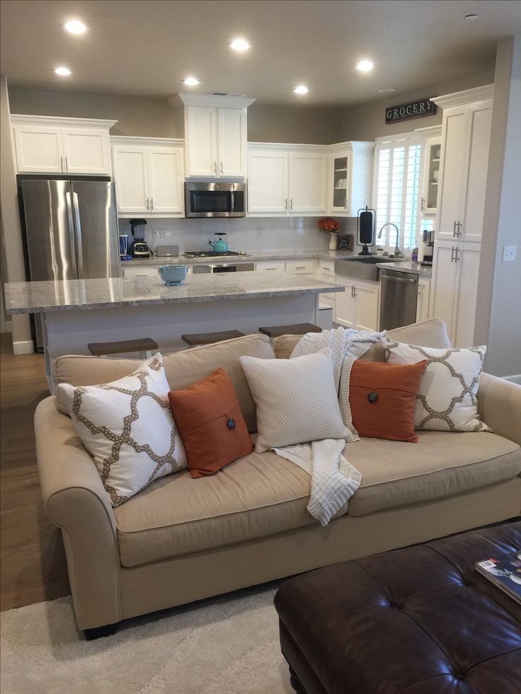 a living room filled with furniture and a kitchen in the backgroung area