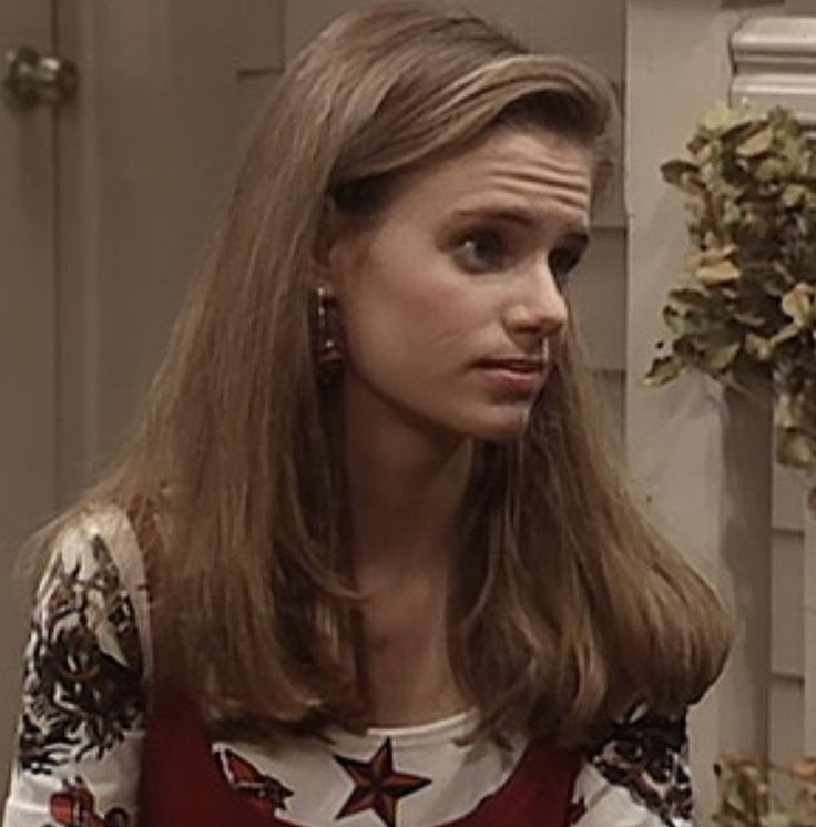 a woman with long hair wearing a red and white top looking at something in front of her