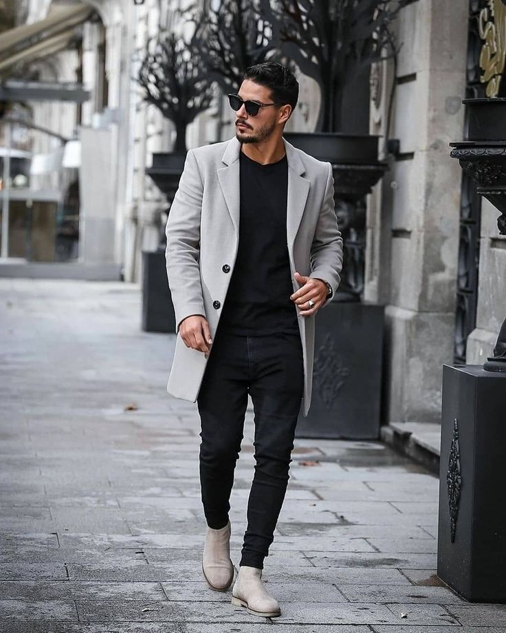 a man walking down the street wearing a gray coat and black pants with white shoes