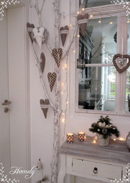 a white table topped with a vase filled with flowers next to a tree covered in lights