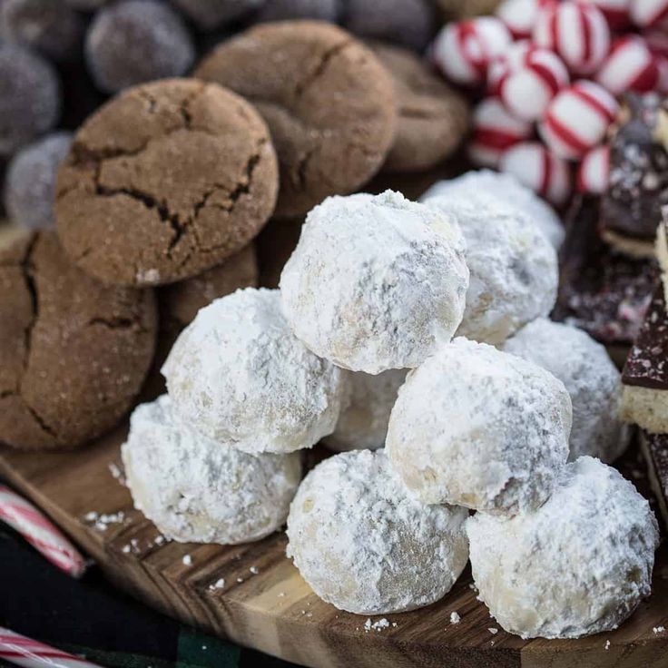 a wooden platter filled with cookies and desserts next to candy caned candies