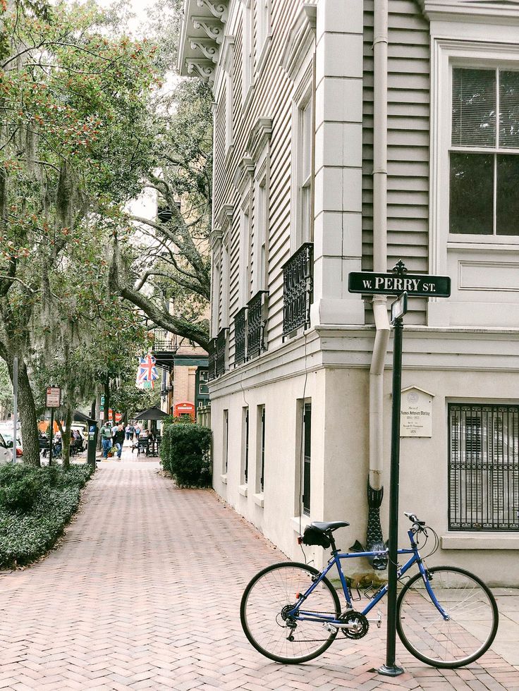 a blue bicycle parked on the side of a street next to a tall white building