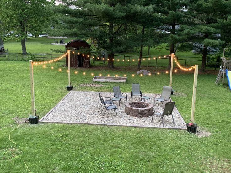 a fire pit surrounded by chairs and string lights in a backyard area with lawn furniture