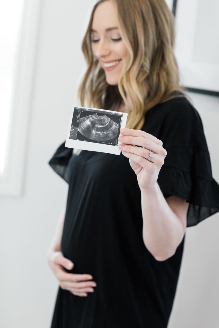 a pregnant woman holding up an old photo