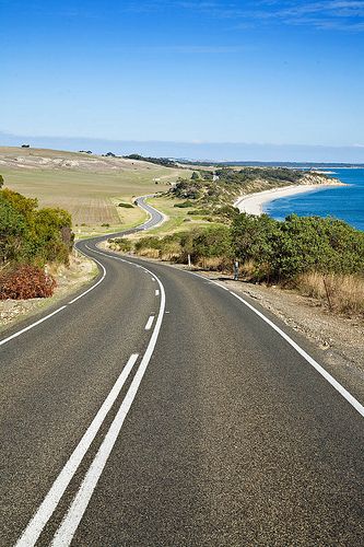 an empty road with the ocean in the background