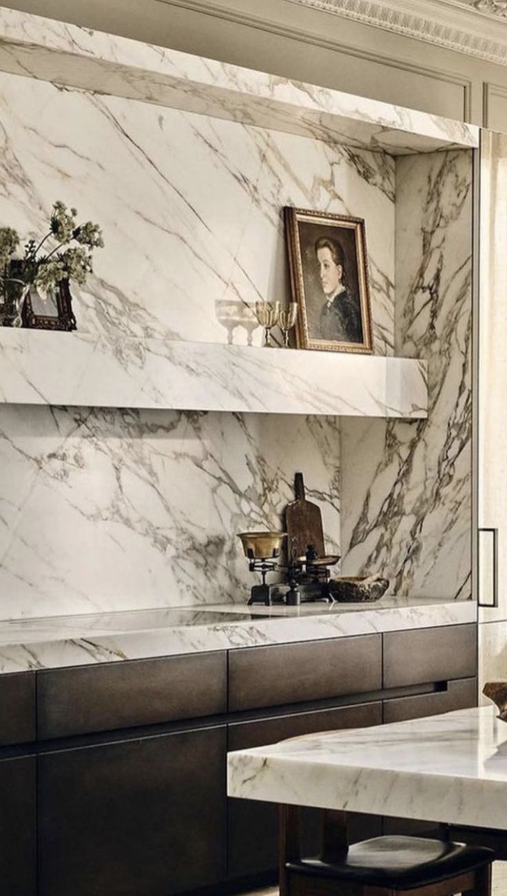 a kitchen with marble counter tops and shelves on the wall, along with an island