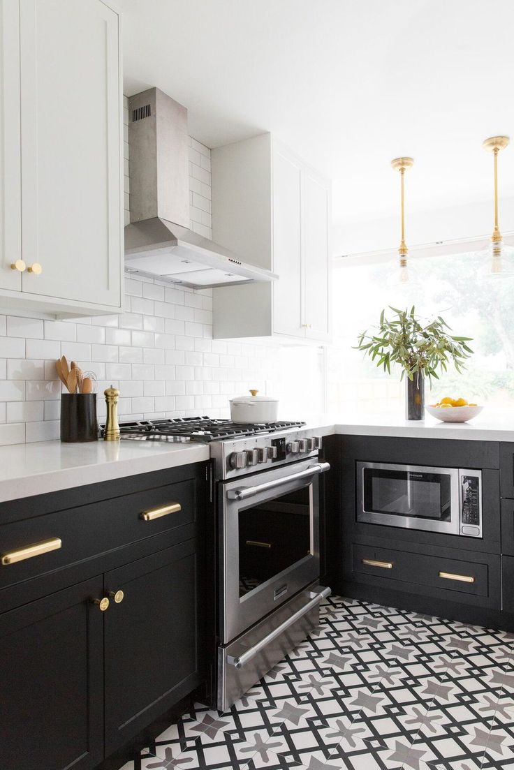 a kitchen with black and white tile flooring and gold trim on the stove top