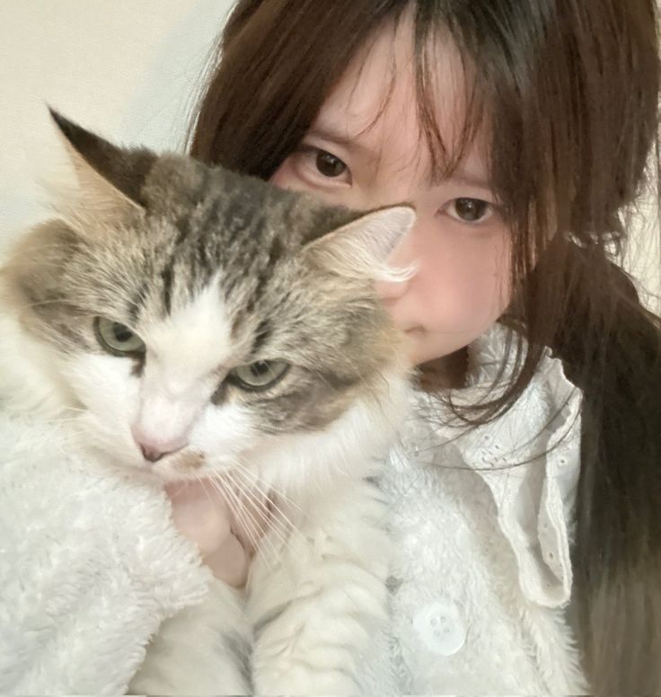 a woman holding a cat in her arms and looking at the camera with an intense look on her face