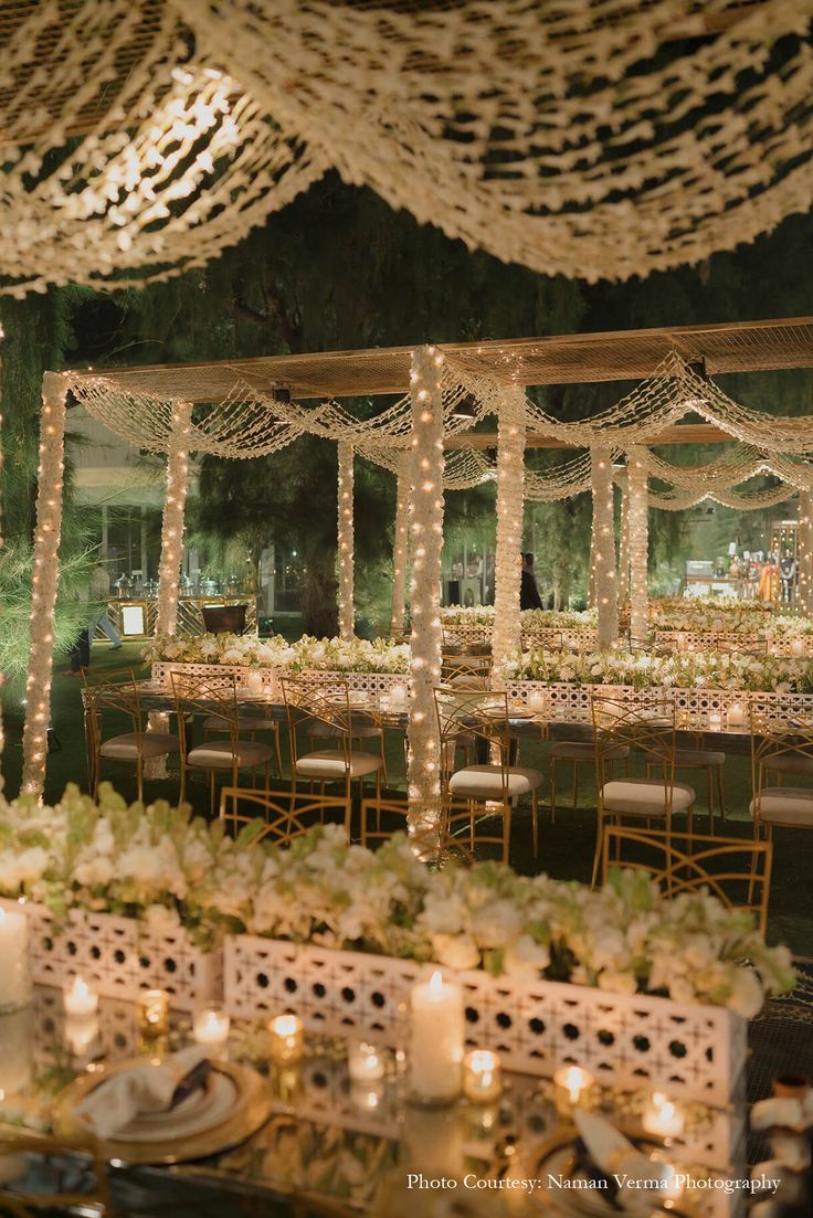 tables and chairs are set up for an event with lights strung from the ceiling over them