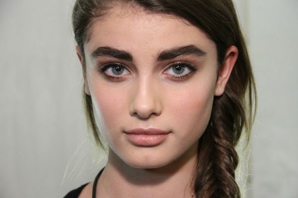 a young woman with braids on her hair and blue eyes looking at the camera