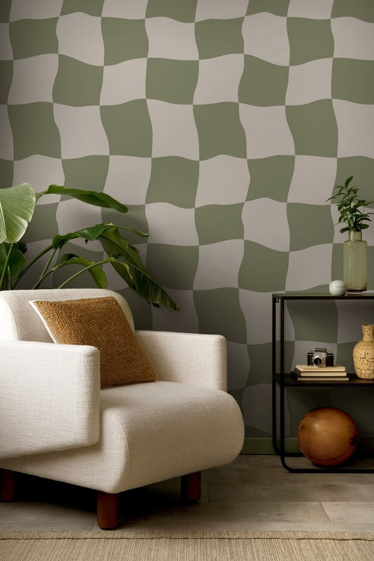 a white chair sitting in front of a wall with green checkered pattern on it