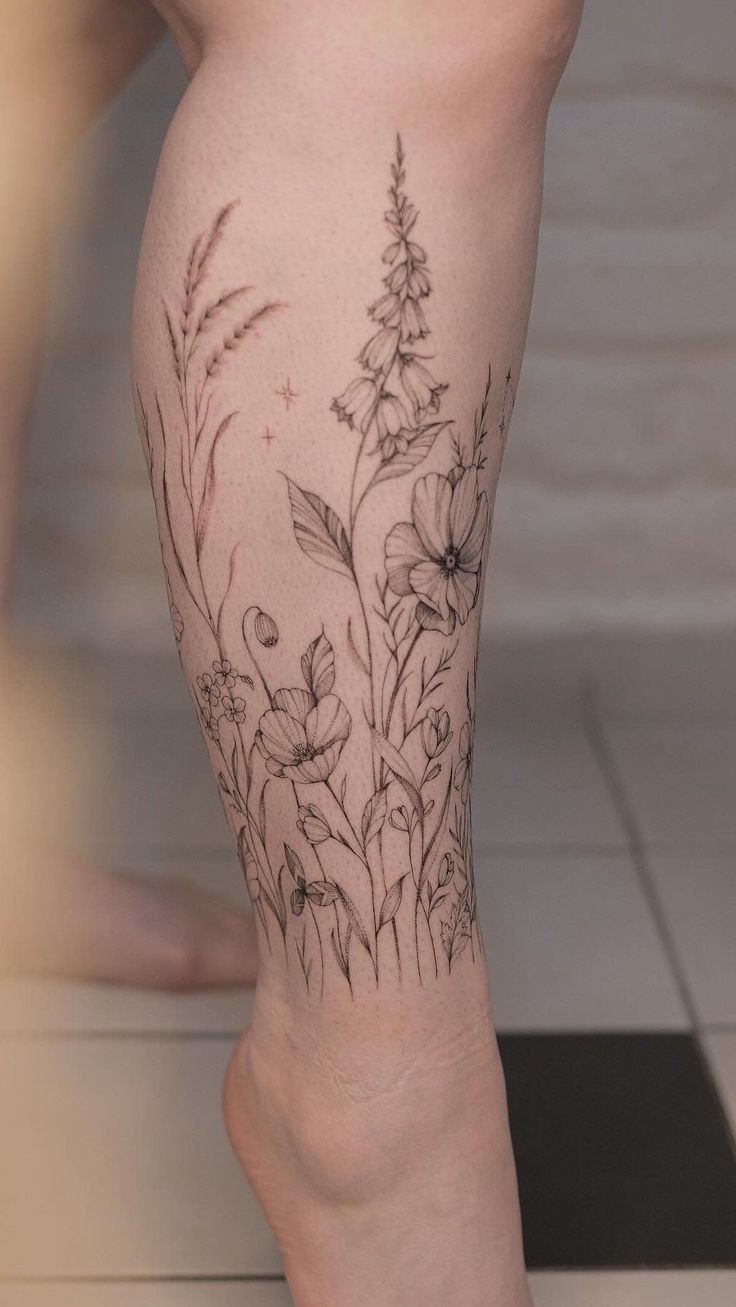 a woman's legs with flowers and leaves tattooed on the side of her leg