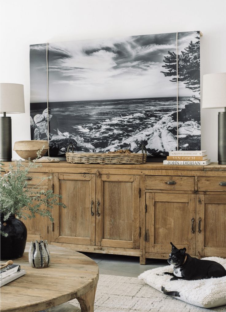 a black cat laying on top of a dog bed in front of a wooden dresser