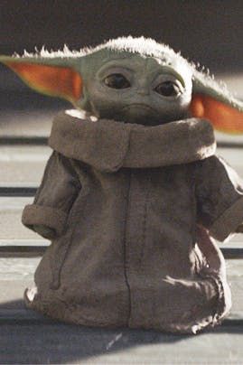 a baby yoda doll sitting on top of a wooden table