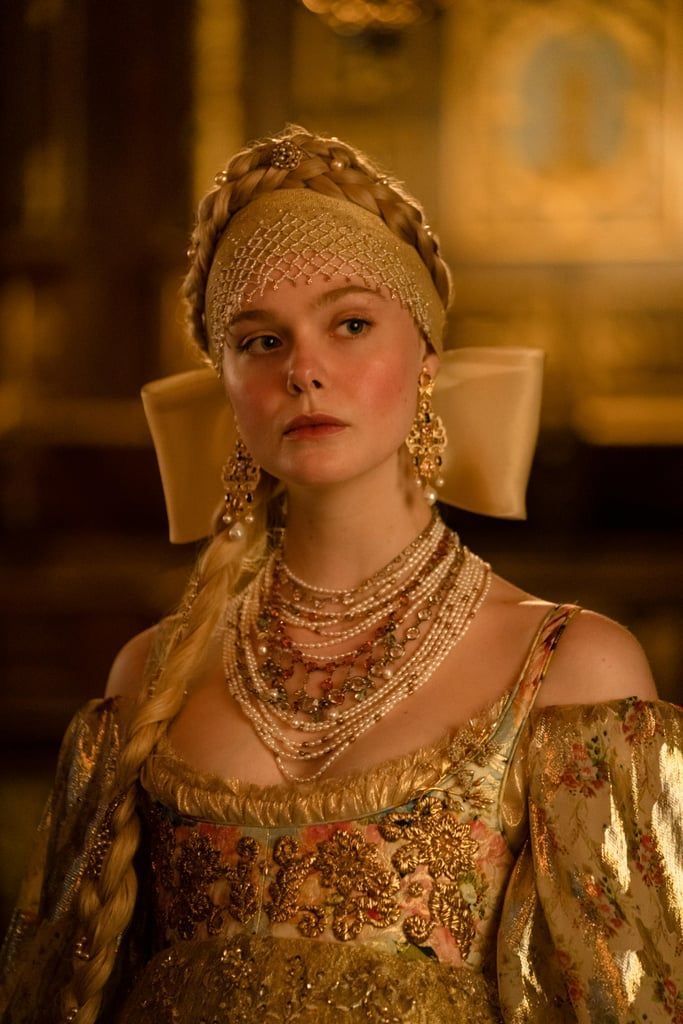 a woman in a gold dress and headpiece with pearls on her hair is looking at the camera