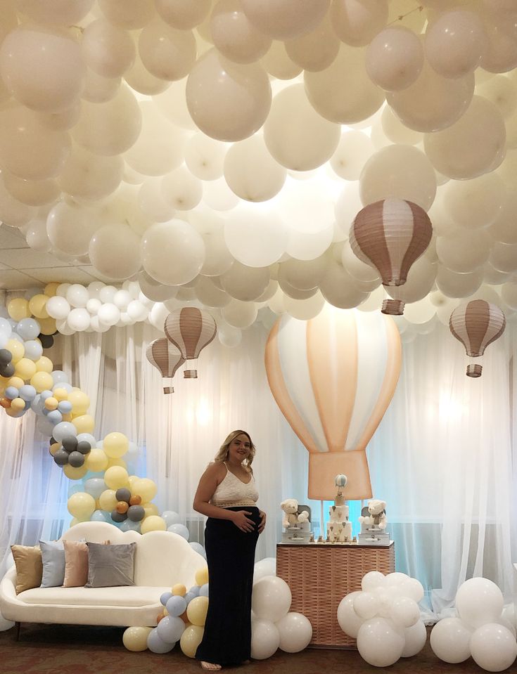 a pregnant woman standing in front of balloons